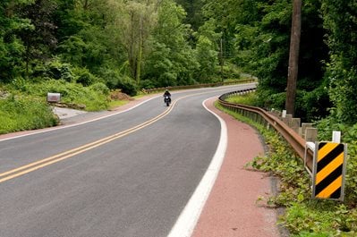 A motorcycle navigates a curve on a rural road.