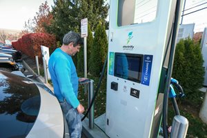 Man stands in front of EV charging port preparing to charge his car.