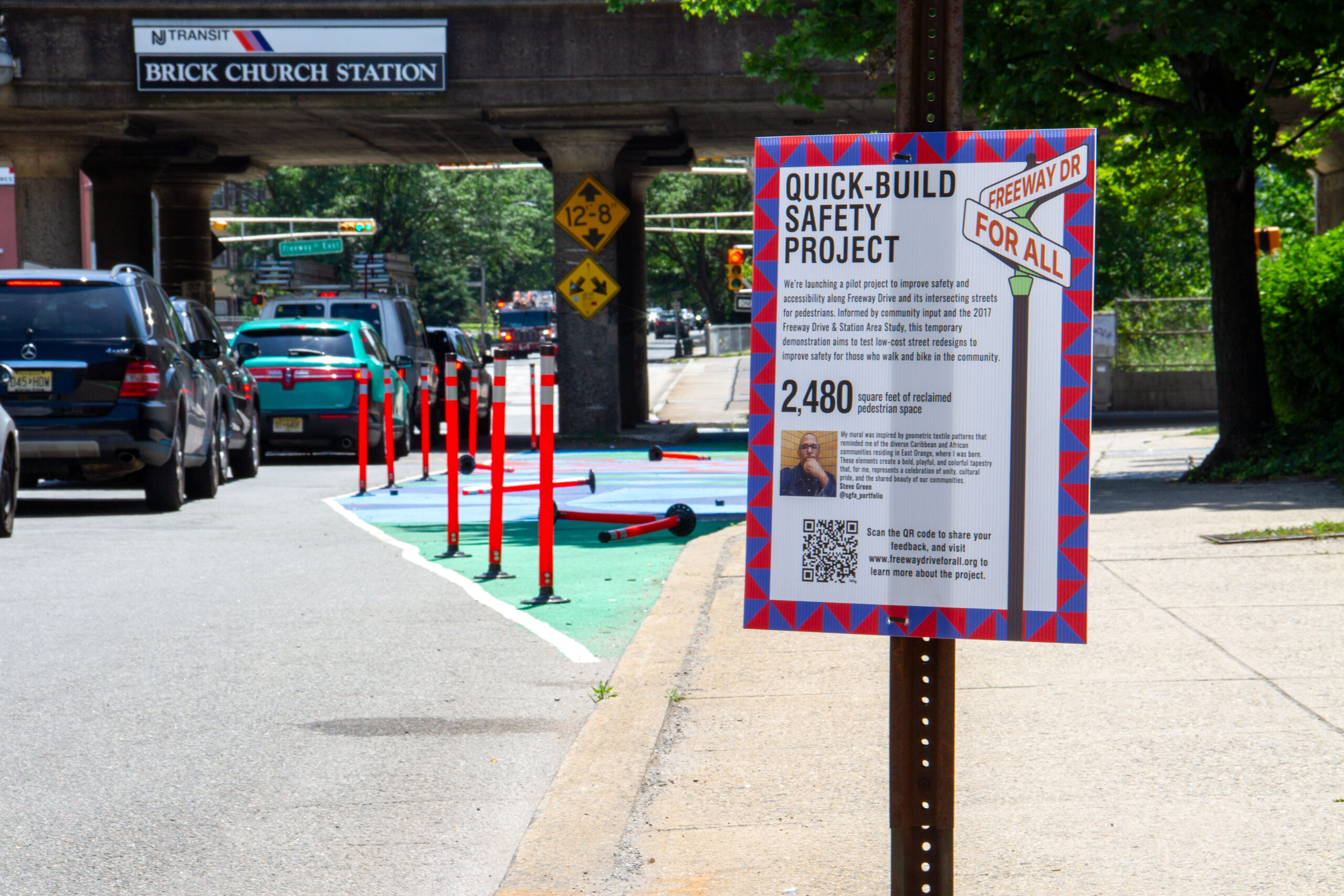 Poster with QR code fastened to pole with delineators and curbside painting project in background as car traffic passes