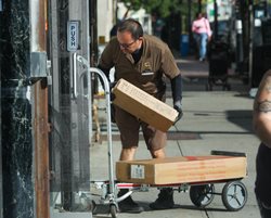 Man delivers several packages with handtruck on sidewalk