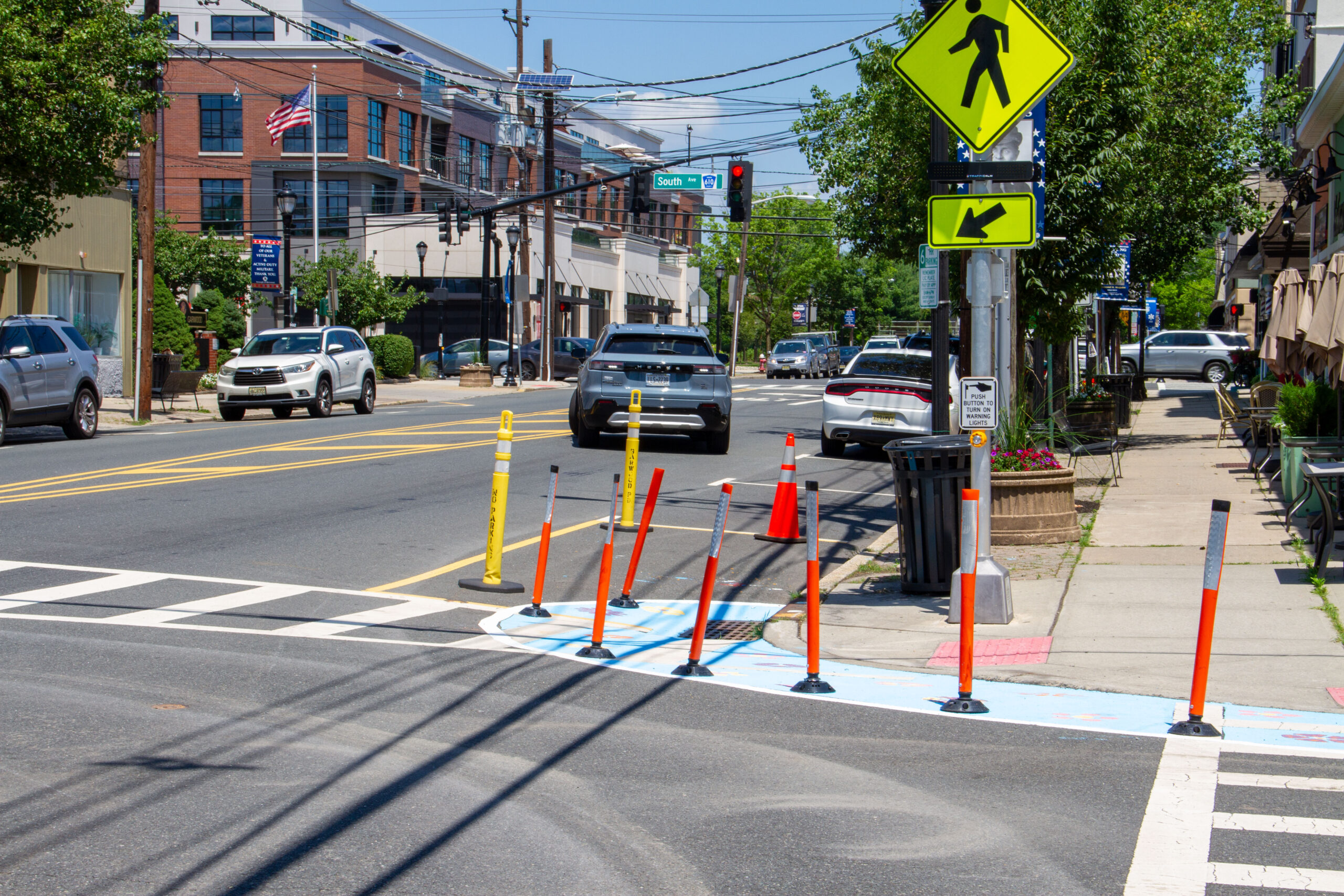 Street corner surrounded with colorful painting and delineators with cars parked curbside in background