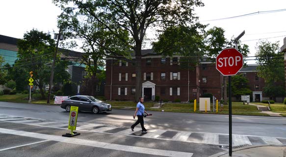 A man walks in a crosswalk as a car passes by.