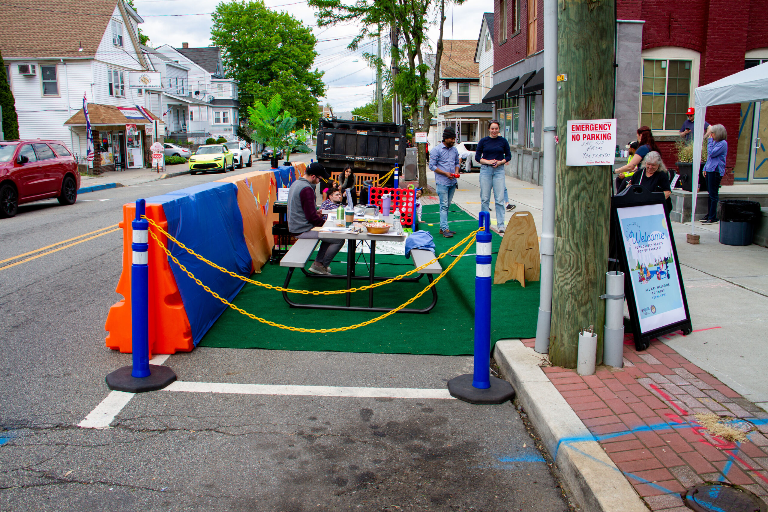 People sit at a table and play games at a temporary park set up in a parking space in Prospect Park as part of a Vibrant Places Program project.