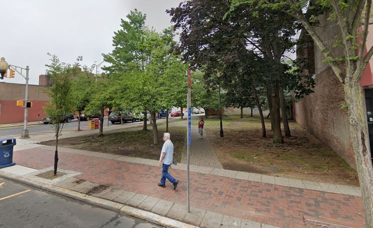 A man walks by Fink Park, a small corner pocket park, in Perth Amboy.