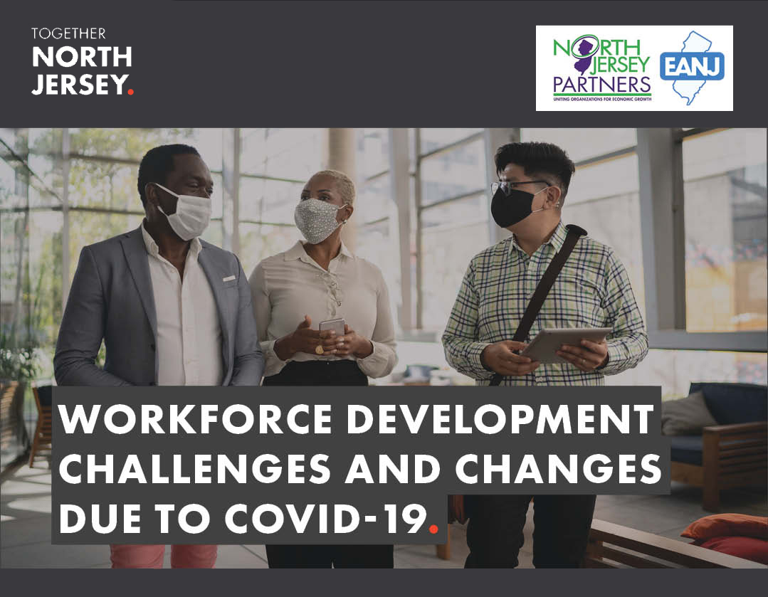 Two men and a woman talk in an office building while wearing face masks.