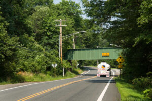 Truck travels on Berkshire Valley Road under railroad bridge with low clearance signs of 11 feet, 5 inches.