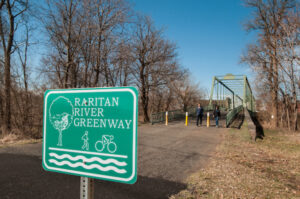 Raritan River Greenway sign ahead of paved path and bridge