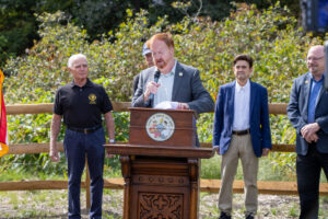 Commissioner John Bartlett speaks at podium during ribbon cutting ceremony for Highlands Rail Trail.