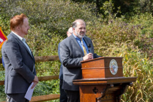 Executive Director David Behrend speaks at podium during ribbon cutting ceremony for Highlands Rail Trail.