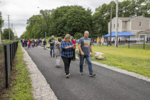 Couple walks along Pompton Valley Rail Trail with people in background