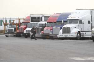 Man walks past series of parked tractor-trailers at Lombardi Service Area, Bergen County.