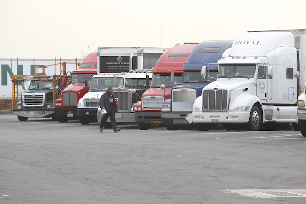 Man walks past series of parked tractor-trailers at Lombardi Service Area, Bergen County.