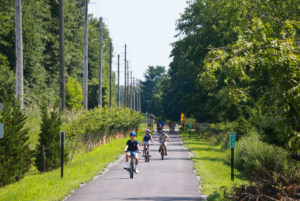 Kids on bikes in distance biking along paved multi-use path, Pompton Valley Rail Trail.